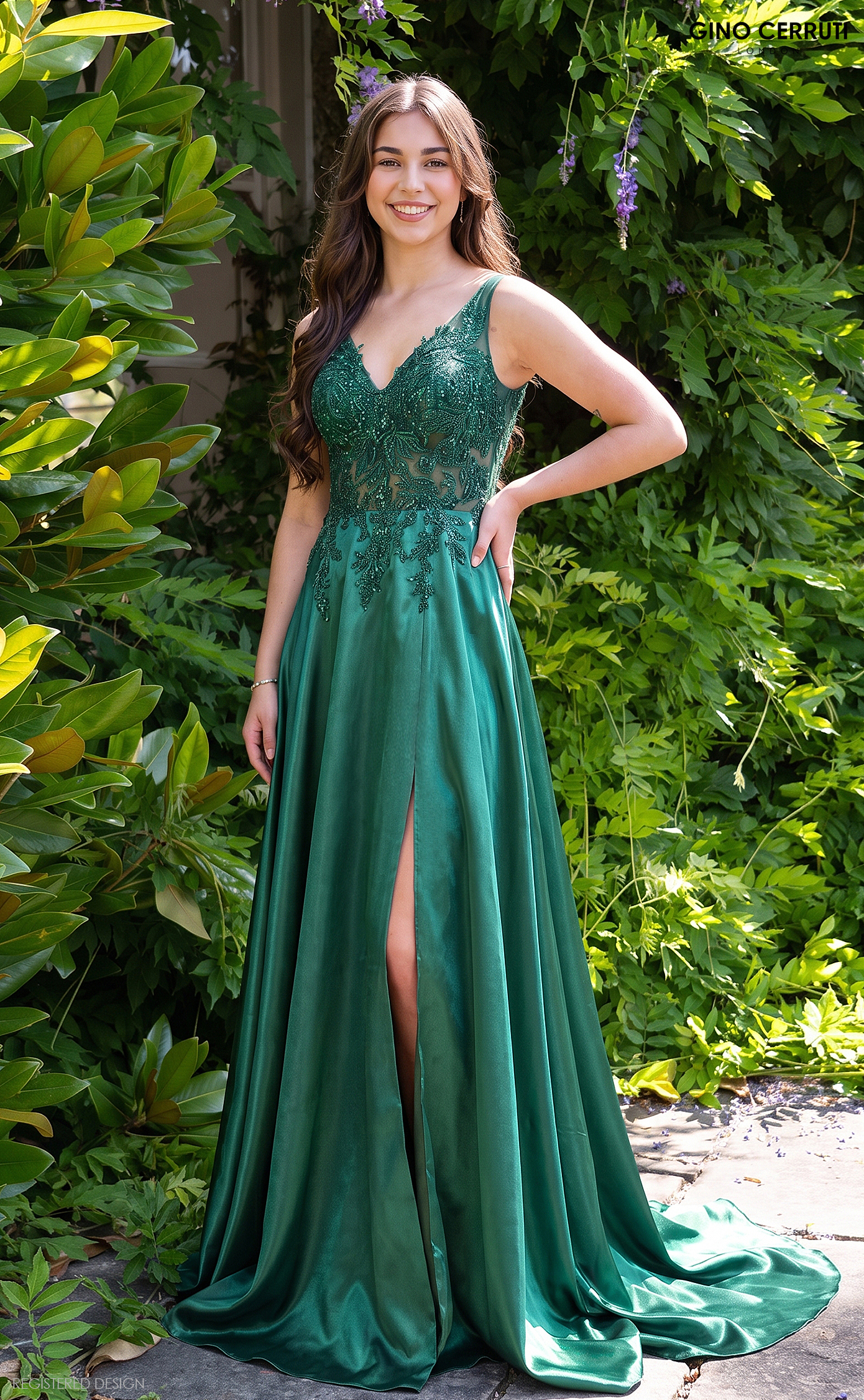Model wearing an elegant emerald green Gino Cerruti floor-length evening gown with a sparkling embellished bodice, V-shaped back and flowing skirt, photographed from behind.